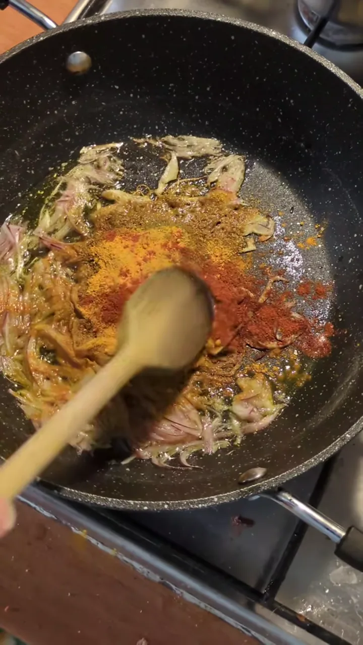 Red bell pepper being added to the spiced onion