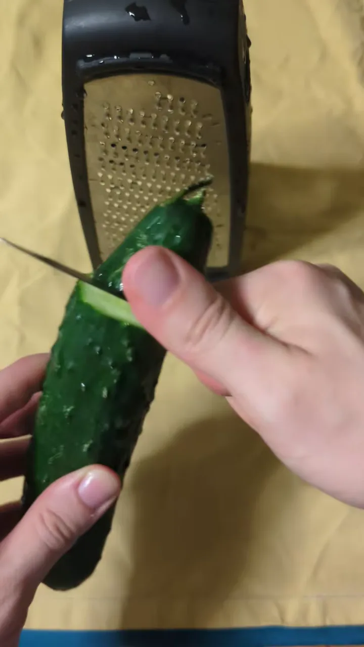 A cucumber being grated over a cloth