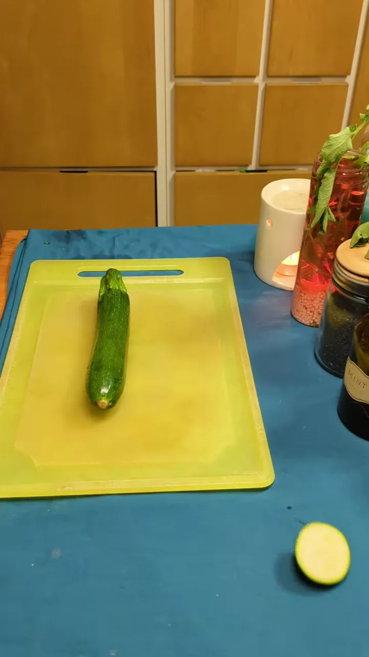 A zucchini being sliced very thinly